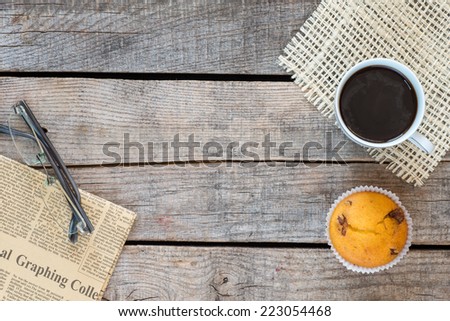 Wooden vintage background. Vintage newspaper and glasses, coffee cup and muffin on old wooden table