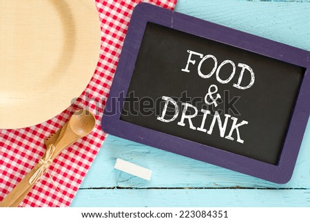 Food & Drink. Chalkboard with wooden spoon and plate on a red checkered tablecloth and text Food & Drink