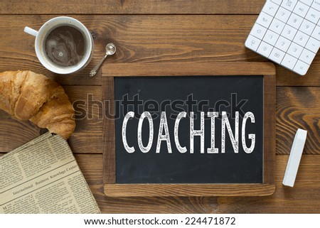Coaching handwritten with white chalk on a blackboard on a wooden background