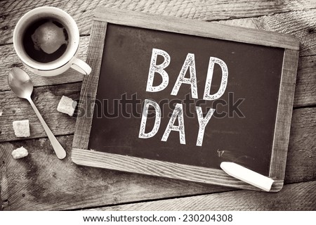 Bad Day sign on Blackboard. Blackboard with Black Friday sign and cup of coffee on wooden background