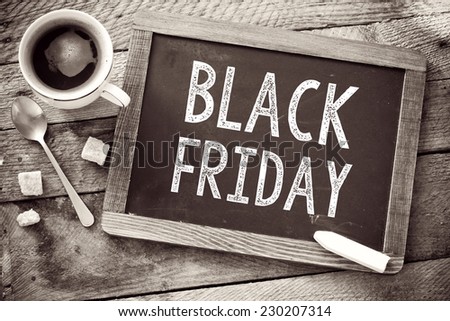 Black Friday sign on Blackboard. Blackboard with Black Friday sign and cup of coffee on wooden background
