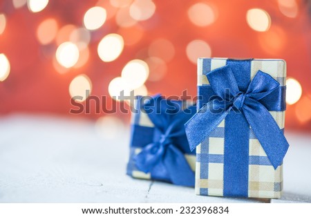 Presents with blue ribbons. Small presents with blue ribbons on red sparkle blurred background.