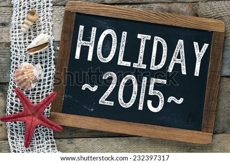 Blackboard with Holiday 2015 inscription and shells on wooden background