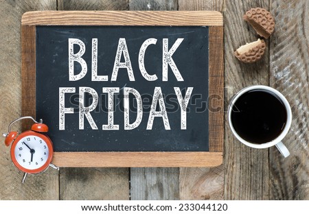 Black friday sign on blackboard with cup of coffee ,cookie and clock on wooden background