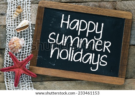 Happy summer holiday. Blackboard with happy summer holiday inscription and shells on wooden background.