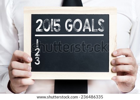 2015 goals background . Idea. Businessman holding board on the background with 2015 goals words