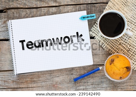 Notebook with teamwork sign and sticker remember on wooden desk with cup of coffee and muffin