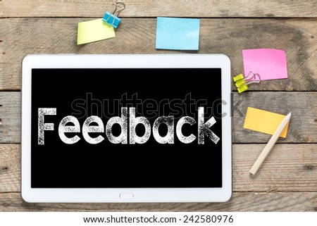 Feedback On Tablet computer. Tablet computer with stickers and feedback on the wooden table