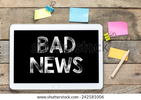 Bad news On Tablet computer. Tablet computer with stickers and bad news on the wooden table