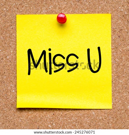 Note with miss you. Blank yellow sticky note with miss you pined on a cork bulletin board.