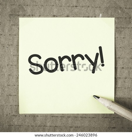 Note with sorry. Note with sorry and pencil on grunge background
