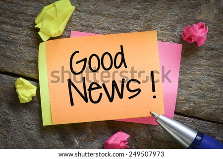 Note with good news! Note with good news! on the wooden background with pen