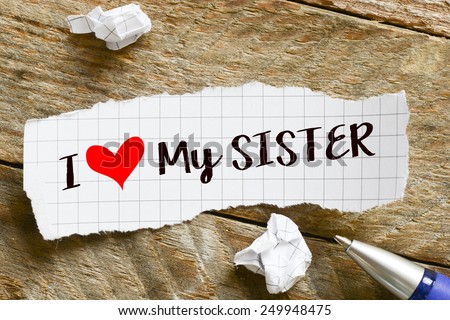 I love my sister Note. Note with I love my sister and red heart on the wooden background with pen