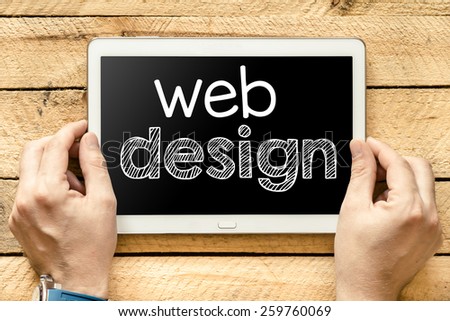Tablet pc with web design. Male hands holding tablet pc with web design on wooden background