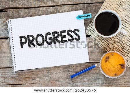 Notebook with grogress and sticker remember on wooden desk with cup of coffee and muffin