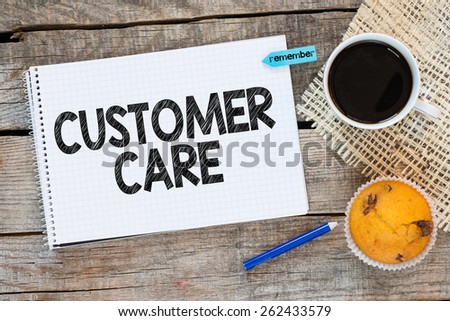 Notebook with customer care and sticker remember on wooden desk with cup of coffee and muffin