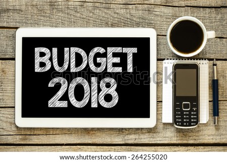 Budget 2018 on tablet pc. Budget 2018 on tablet pc with cup of coffee, notebook,mobile phone and pen on wooden background