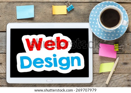 Web design on Tablet computer. Tablet computer with stickers,cup of coffee and web design on the wooden table