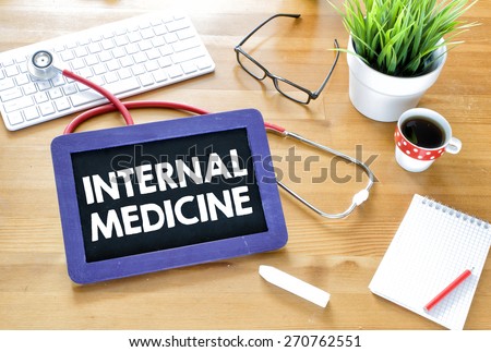 Handwritten internal-medicine on blackboard. Handwritten internal-medicine with chalk on blackboard,stethoscope, keyboard,notebook,glasses,cup of coffee and green plant on wooden background