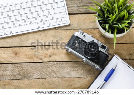 Old camera with keyboard. Old camera with keyboard and green plant on wooden background