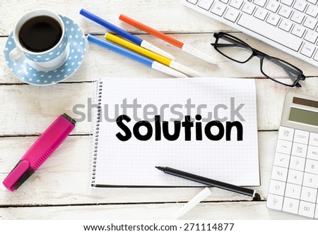 Solution word and cup of coffee.  Solution word Written on white paper with cup of coffee ,keyboard , calculator,glasses, felt pens on wooden background