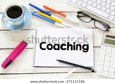 Coaching word with cup of coffee. Coaching word Written on white paper with cup of coffee ,keyboard , calculator,glasses, felt pens on wooden background