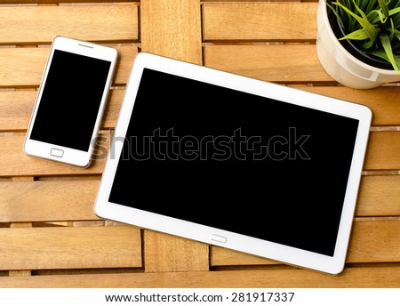 Smart phone and tablet pc with plant. Smart phone and tablet pc with green plant on wooden table.