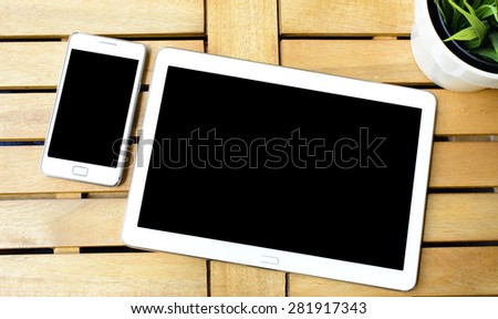 Smart phone and tablet pc with plant. Smart phone and tablet pc with green plant on wooden table.
