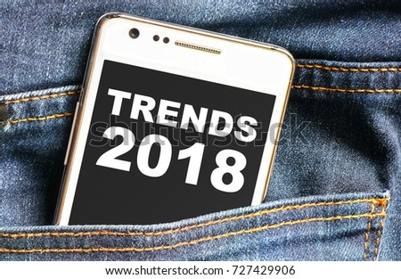 Trends 2018 inscription on phone screen / Smartphone in front jeans pocket with trends 2018 inscription