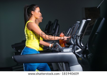 Attractive young woman runs on a treadmill, in fitness sport club