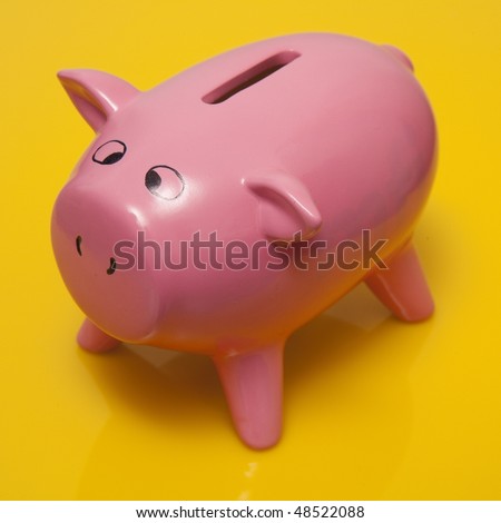 Pink piggy bank style money box on a yellow studio background.
