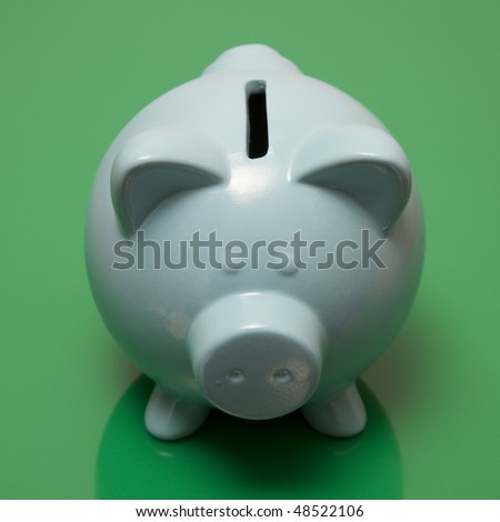 Blue piggy bank style money box on a green studio background.