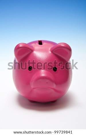 Pink piggy bank or money box on a graduated blue studio background.