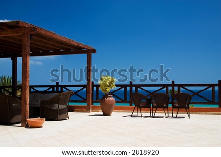 Balcony with 3 rattan chairs and ocean at the background