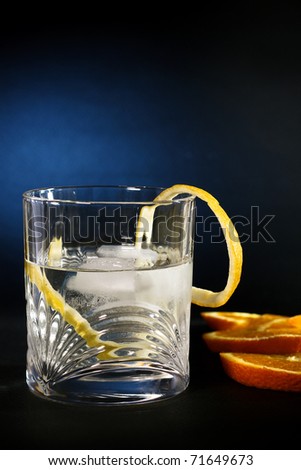 Cold vodka in a glass, with decor oranges and lemon, in black blue  background, part of art beverage background
