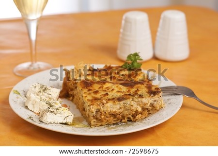 Pastitsio greek food on a table, wine alcohol drink salt and pepper
