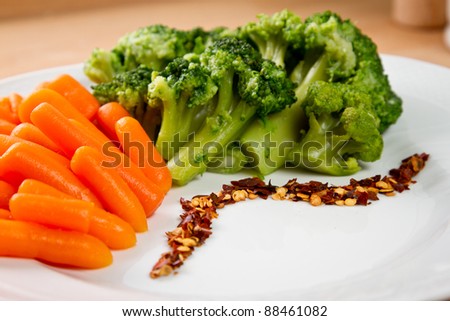 Steamed broccoli and baby carrots with red pepper in a white dish