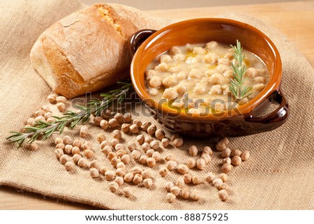 Bowl of pasta and chickpea soup with bread and rosemary over a jute bag