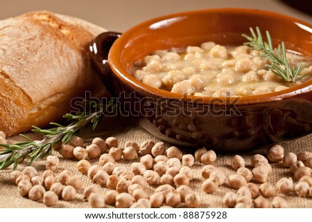 Bowl of pasta and chickpea soup with bread and rosemary over a jute bag