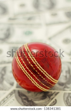 Red cricket on ball on money