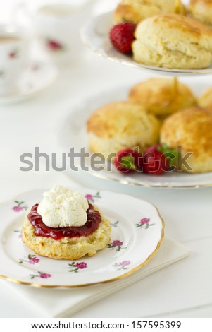 English Cream tea scene with scones, Cornish style, on china plate with cake stand behind. Part of a series showing the preparation of scones.