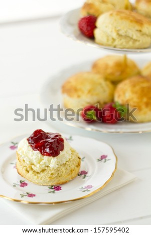 English Cream tea scene with scones, Devonshire style, on china plate with cake stand behind. Part of a series showing the preparation of scones.