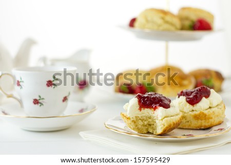 English Cream tea scene with scones, Devonshire style, with a bite taken out. Part of a series showing the preparation of scones.
