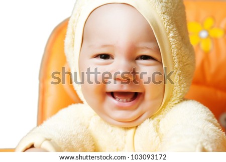close up portraiy of baby boy smiles his widest smile ever as he laughs while sitting in his highchair