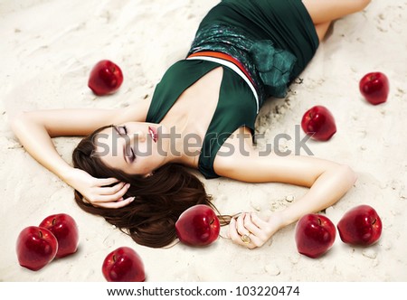 woman with red apples on the sand in green dress