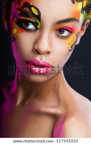 portrait of the dark-skinned girl with unusual make-up on dark background