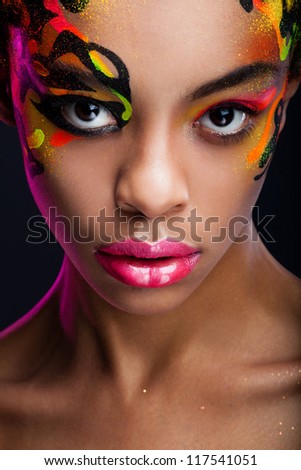 portrait of the dark-skinned girl with unusual make-up on dark background