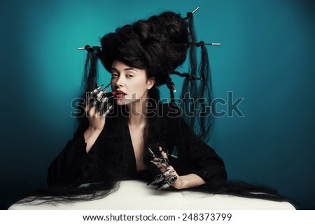 girl with fluffy hair sitting at the table and paints lips