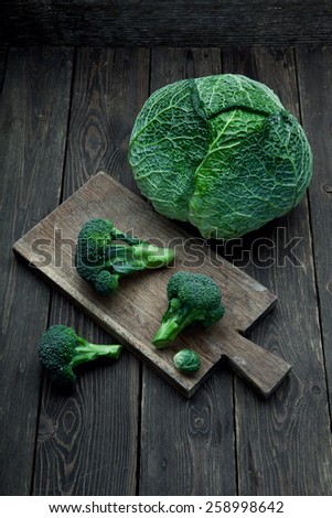 Different kinds of cabbage: Savoy cabbage, Broccoli and brussels sprouts on wooden background