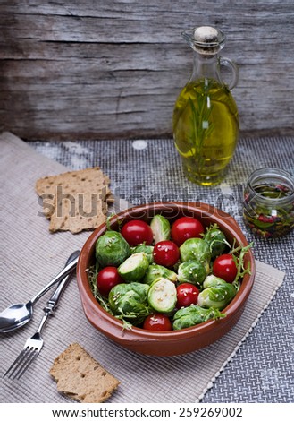 Fresh organic salad of Brussels sprouts and cherry tomatoes in bowl on vintage background